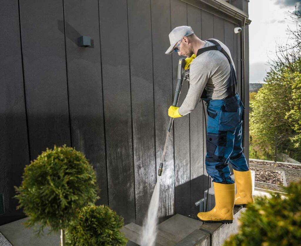 person power washing a house steps